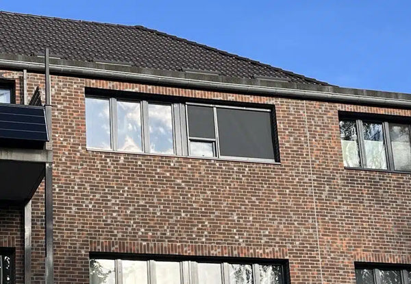 Sonnenschutz Rollo an der Fassade eines Wohngebäudes schützt die Fenster vor direkter Sonneneinstrahlung.